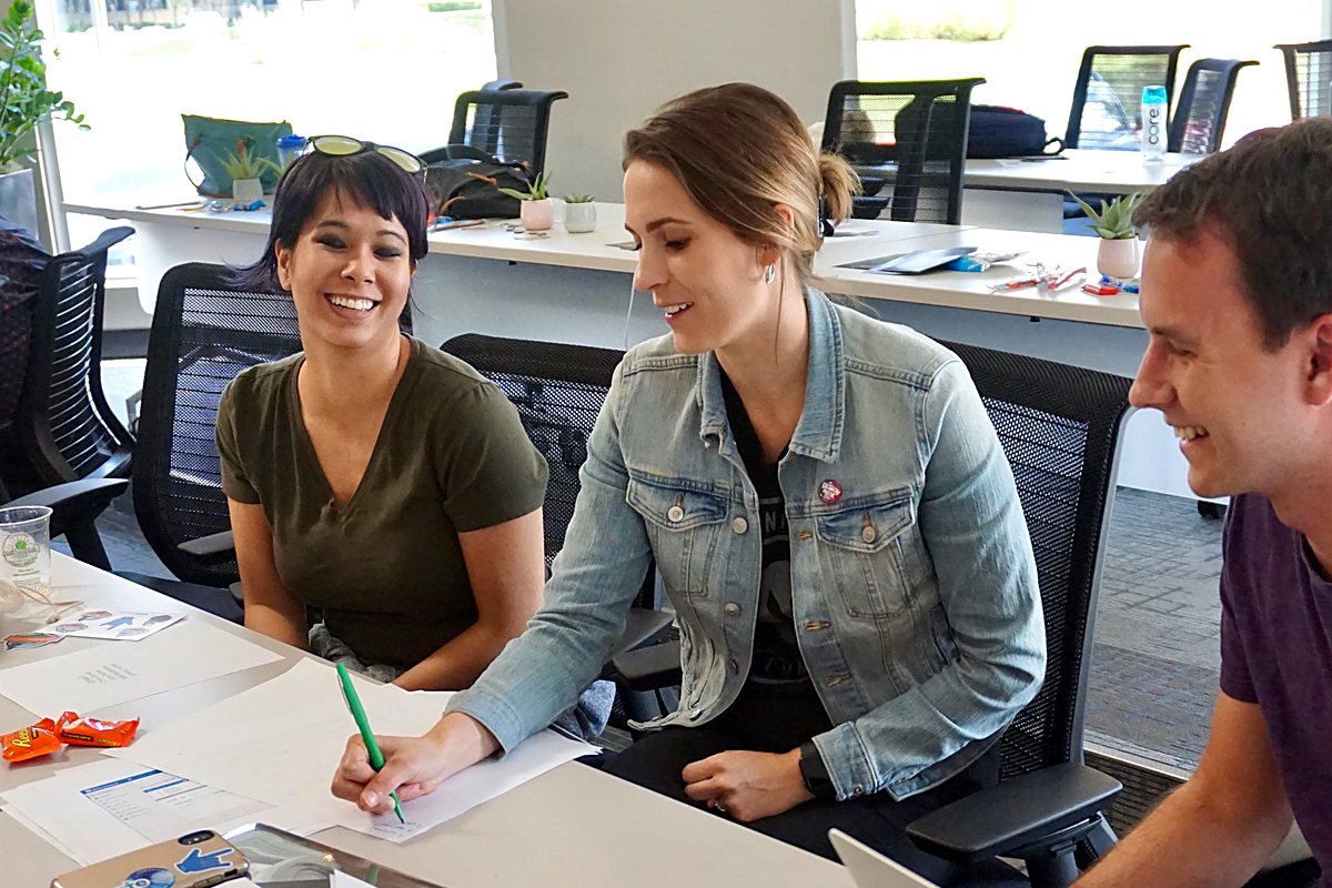 Brittany sketching ideas on paper with two colleagues during a work session